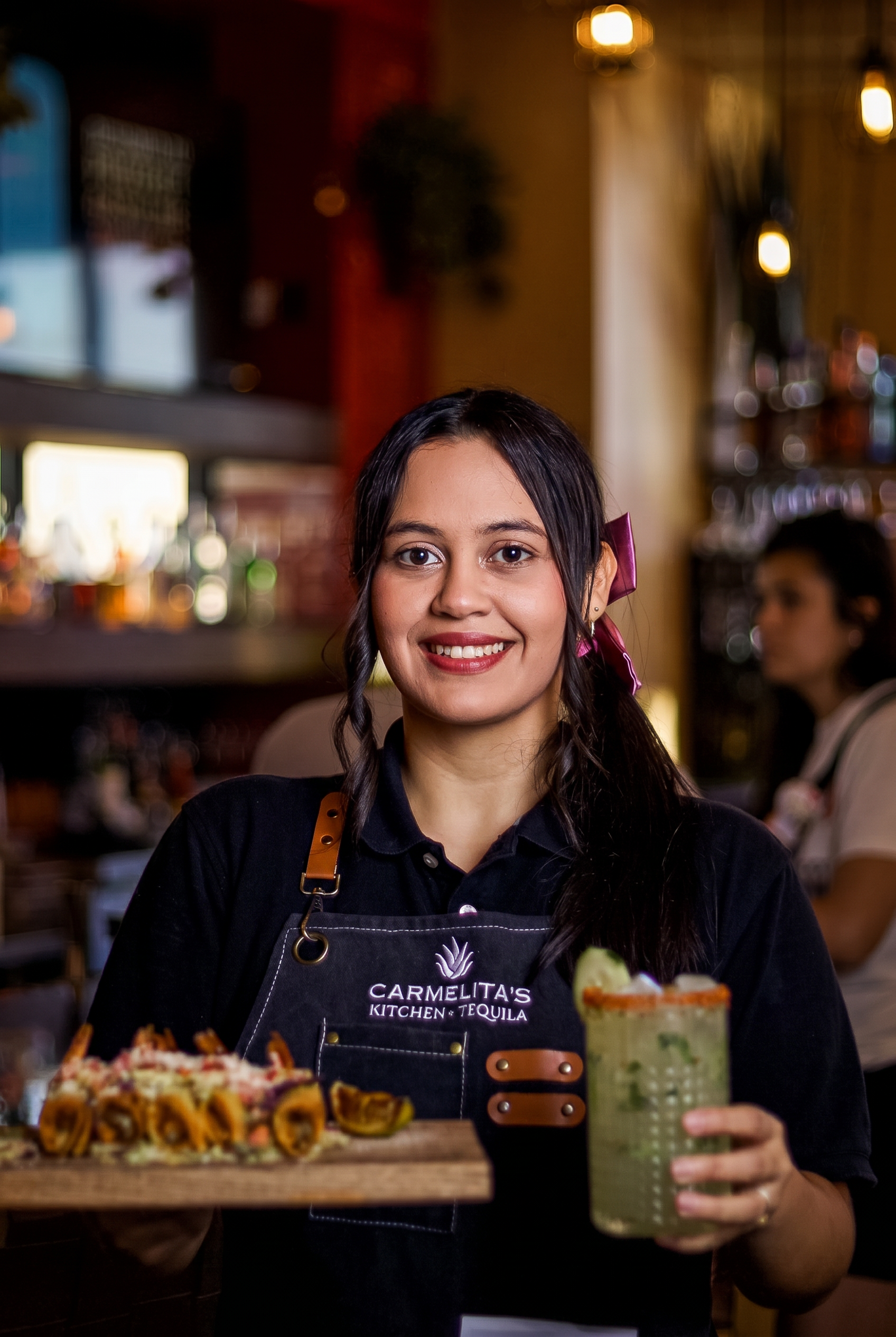 Houston restaurant photography of a smiling server presenting sushi rolls and a margarita cocktail