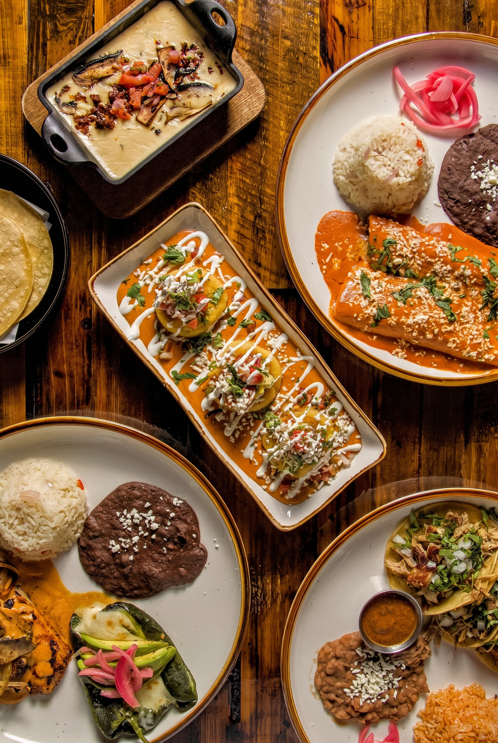 Houston food photography overhead spread of Mexican enchiladas, queso fundido, sopes and tacos on a wooden table