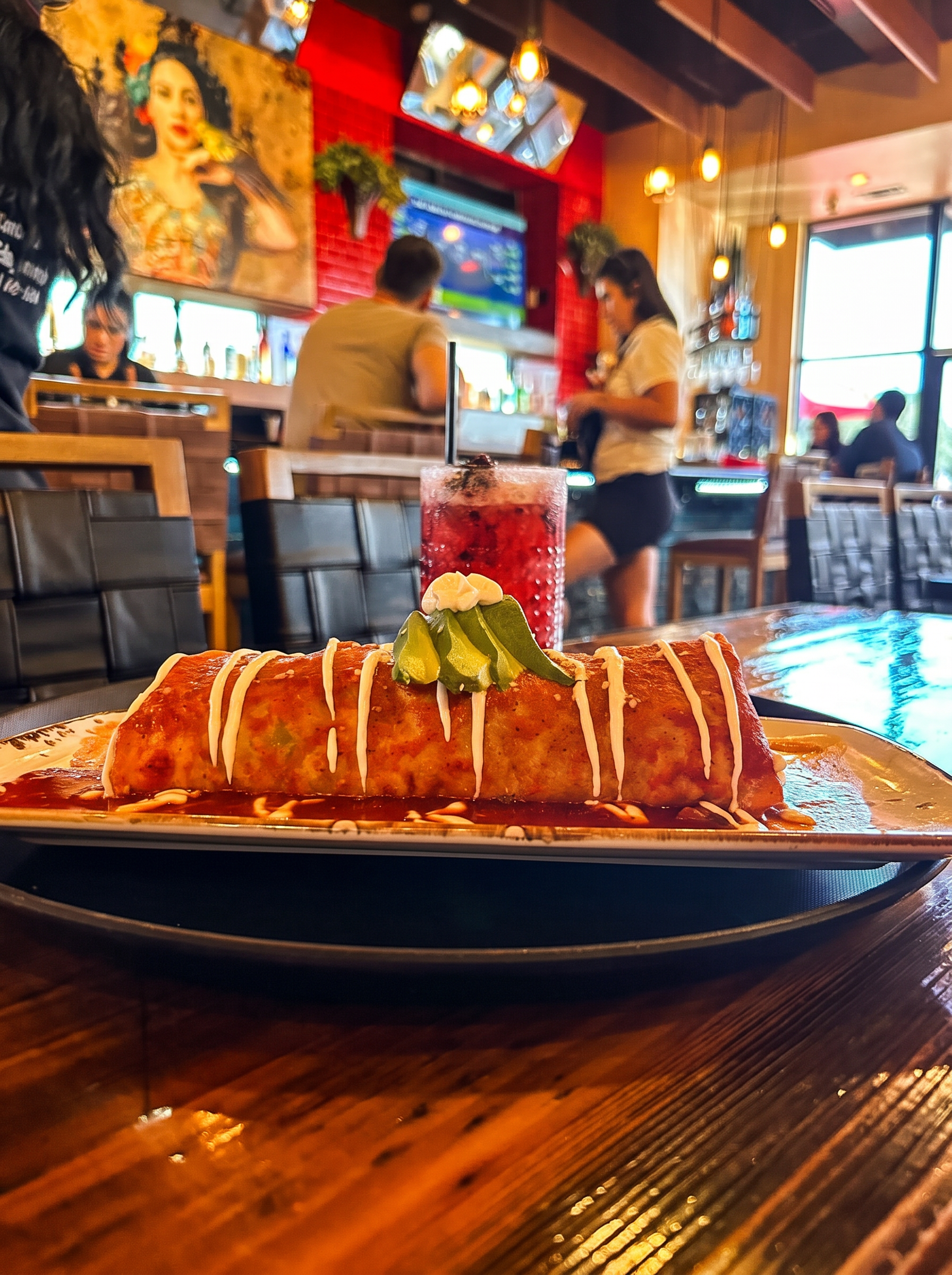 Houston food photography of a chimichanga burrito in red sauce with a berry cocktail at a restaurant